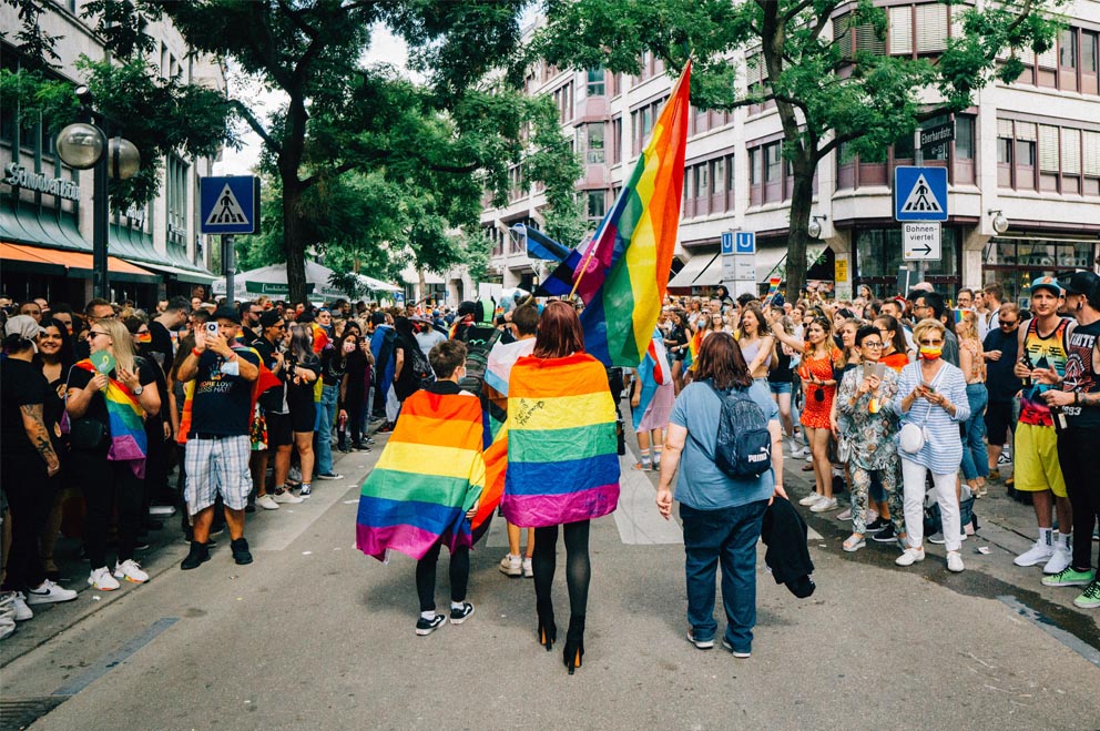 Menschen mit Regenbogenflaggen bei einer Demo.