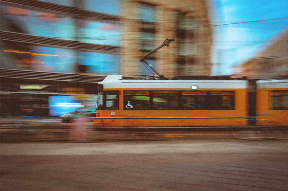 Eine gelbe Straßenbahn fährt durch eine Stadt.