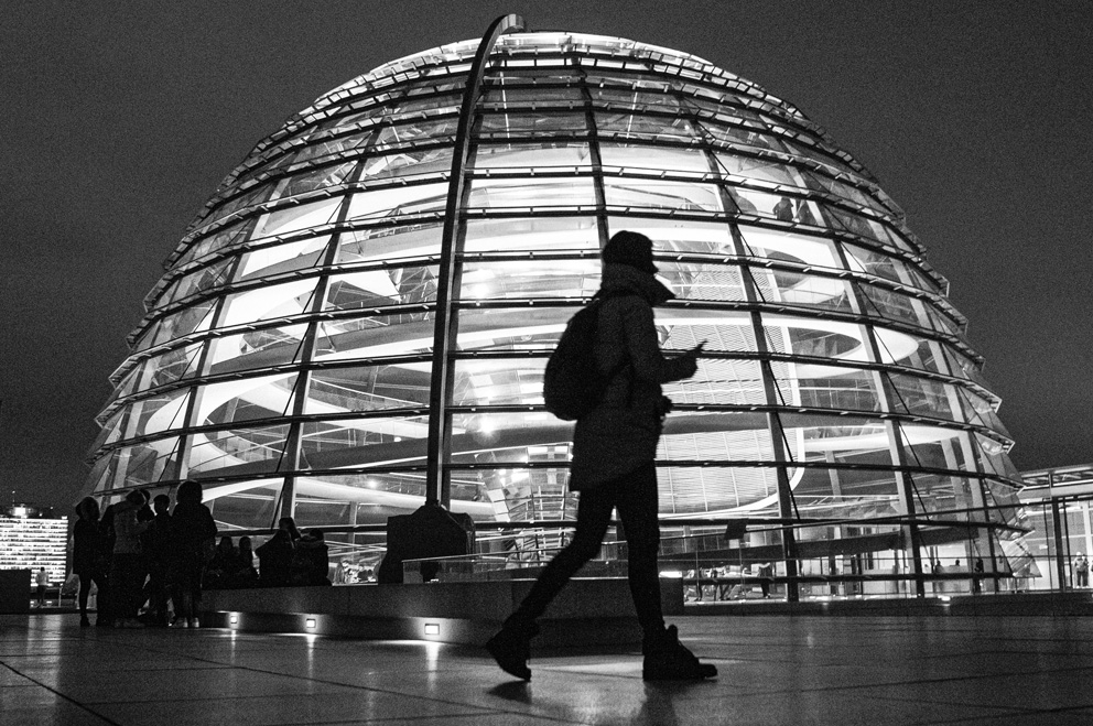 Silhoutte der Reichstagskuppel, davor eine junge Person.