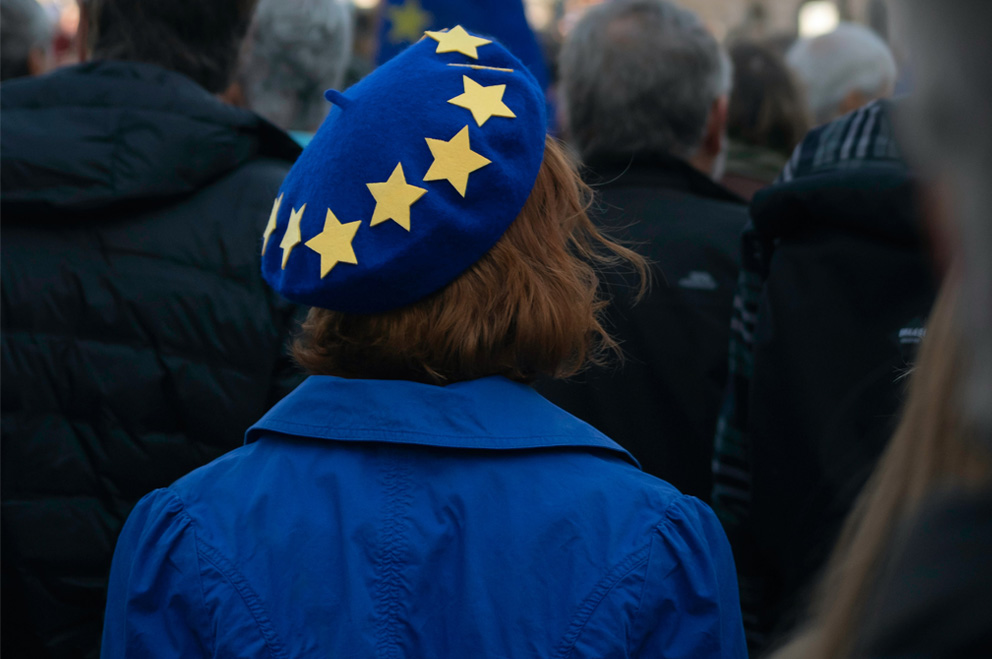 Junge Person von hinten mit blauem Mantel und blauer Mütze mit gelben Sternen.