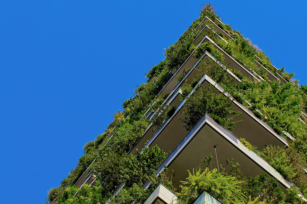 Von unten nach oben Blick auf ein Hochhaus mit vielen grünen Pflanzen auf Balkons entlang der ganzen Fassade