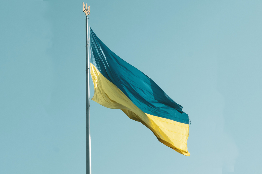 Ukrainische Flagge am Mast vor blauem Himmel.