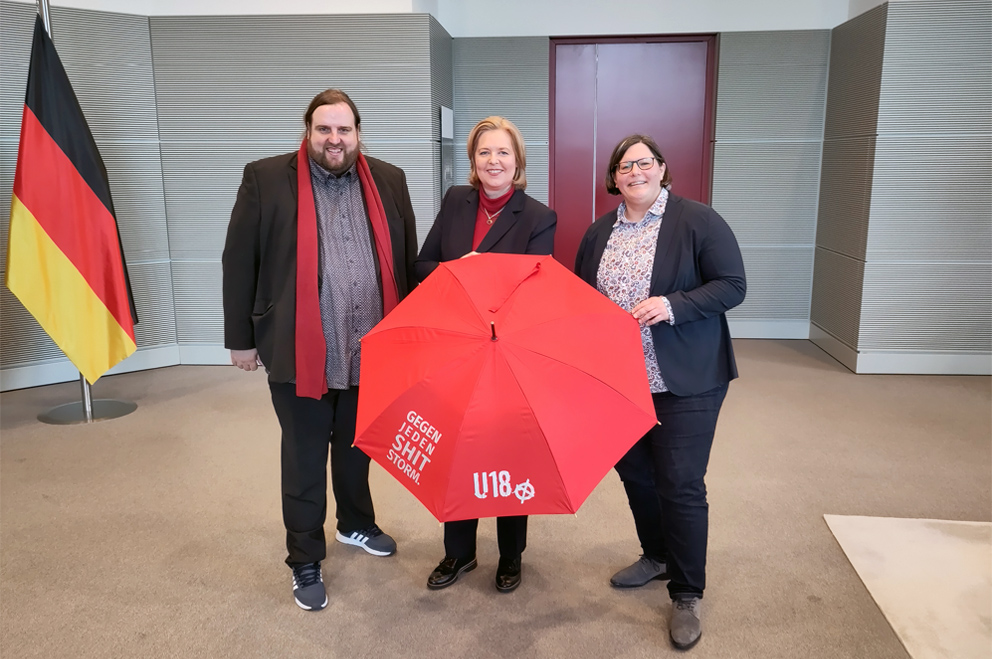 Bärbel Bas mit Wendelin Haag und Daniela Broda. Die Bundestagspräsidentin hält einen roten Regenschirm mit der Aufschrift "Gegen jeden Shit Storm. U18"
