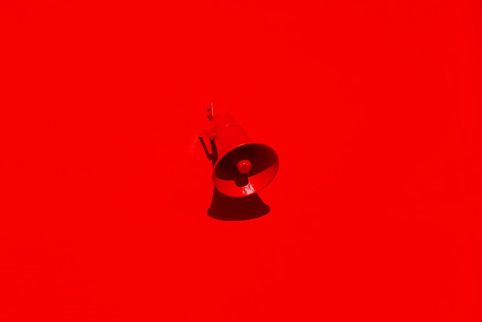 Leuchtend roter Megafon-Lautsprecher an einer roten Wand
