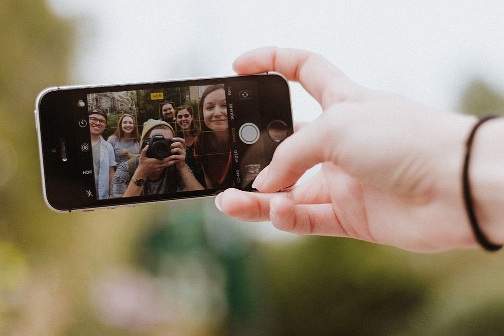 Jugendliche beim Selfie mit Smartphone und Fotokamera im Fokus.