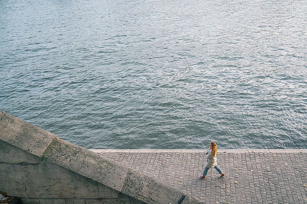 Junge Frau geht alleine am Flussufer entlang